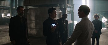 Movie still from “Charlie's Angels” (2019), directed by Elizabeth Banks – A man in a suit holding a blue object in his hand; Medium shot, Over the shoulder angle