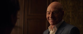 Movie still from “Charlie's Angels” (2019), directed by Elizabeth Banks – An older man with a bald head smiling for the camera; Close Up shot, Over the shoulder angle