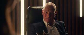 Movie still from “Charlie's Angels” (2019), directed by Elizabeth Banks – An older man sitting in an office chair; Close Up shot, Over the shoulder angle