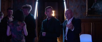 Movie still from “Charlie's Angels” (2019), directed by Elizabeth Banks – A man standing next to another man wearing a suit; Medium shot, Over the shoulder angle