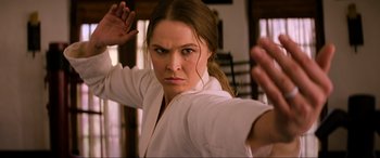 Movie still from “Charlie's Angels” (2019), directed by Elizabeth Banks – A woman in a white shirt is doing a karate move; Close Up shot, Over the shoulder angle