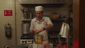 Movie still from “Cheaper by the Dozen” (2022), directed by Gail Lerner – A man in a kitchen holding a basket of food; Medium shot, Low angle