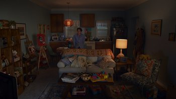 Movie still from “Cheaper by the Dozen” (2022), directed by Gail Lerner – A man standing in a living room next to a couch; Wide shot, High angle