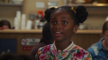 Movie still from “Cheaper by the Dozen” (2022), directed by Gail Lerner – A little girl with two ponytails and a floral shirt; Close Up shot, Over the shoulder angle