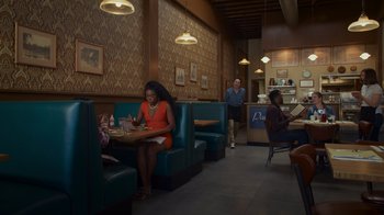 Movie still from “Cheaper by the Dozen” (2022), directed by Gail Lerner – A woman sitting at a table in front of a man; Extreme Wide shot, High angle