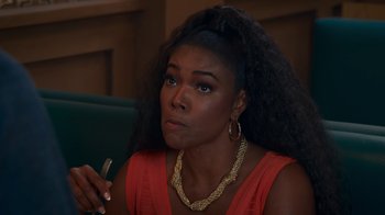 Movie still from “Cheaper by the Dozen” (2022), directed by Gail Lerner – A black woman with long black hair is smoking a cigarette; Close Up shot, Over the shoulder angle