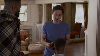 Movie still from “Cheaper by the Dozen” (2022), directed by Gail Lerner – A young man is holding a cell phone in his hand; Medium shot, Over the shoulder angle