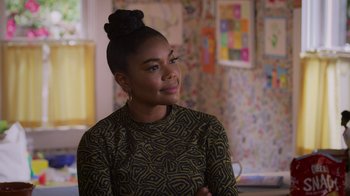 Movie still from “Cheaper by the Dozen” (2022), directed by Gail Lerner – A woman with a bun is sitting in front of a wall; Close Up shot, Over the shoulder angle