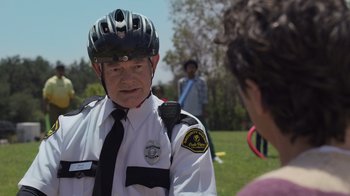 Movie still from “Cheaper by the Dozen” (2022), directed by Gail Lerner – A police officer wearing a bicycle helmet talking to a woman; Close Up shot, Over the shoulder angle