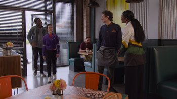 Movie still from “Cheaper by the Dozen” (2022), directed by Gail Lerner – A group of people standing around a table; Wide shot, Over the shoulder angle