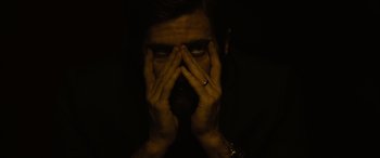 Movie still from “Enemy” (2013), directed by Denis Villeneuve – A man with his hands covering his face; Close Up shot, Low angle