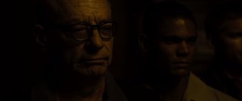 Movie still from “Enemy” (2013), directed by Denis Villeneuve – A man with glasses is looking at the camera; Close Up shot, Over the shoulder angle