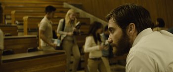 Movie still from “Enemy” (2013), directed by Denis Villeneuve – A group of people standing in a room; Medium shot, Over the shoulder angle