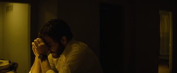 Movie still from “Enemy” (2013), directed by Denis Villeneuve – A man sitting in a dark room with his head on his hand; Close Up shot, Low angle