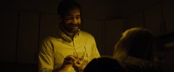 Movie still from “Enemy” (2013), directed by Denis Villeneuve – A man holding a wine glass in his hand; Close Up shot, Over the shoulder angle