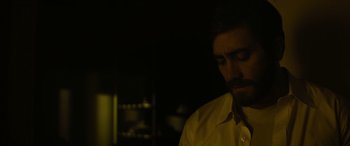 Movie still from “Enemy” (2013), directed by Denis Villeneuve – A man in a white shirt is in a dark room; Close Up shot, Low angle