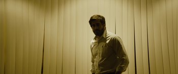 Movie still from “Enemy” (2013), directed by Denis Villeneuve – A man standing in front of a wall of blinds; Medium shot, Low angle