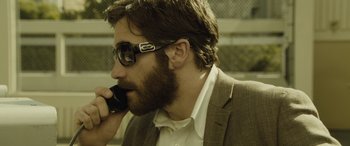 Movie still from “Enemy” (2013), directed by Denis Villeneuve – A man with a beard talking on a cell phone; Close Up shot, Low angle