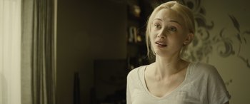 Movie still from “Enemy” (2013), directed by Denis Villeneuve – A woman with blonde hair and a white shirt looking at the camera; Close Up shot, Over the shoulder angle