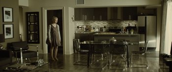 Movie still from “Enemy” (2013), directed by Denis Villeneuve – A woman standing in front of a dining room table; Wide shot, Over the shoulder angle