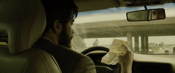 Movie still from “Enemy” (2013), directed by Denis Villeneuve – A man sitting in the drivers seat of a car looking at a piece of paper; Close Up shot, Over the shoulder angle