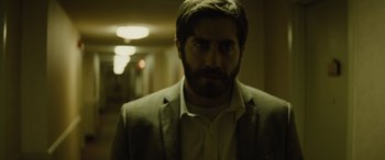 Movie still from “Enemy” (2013), directed by Denis Villeneuve – A man with a beard and a suit and tie; Close Up shot, Low angle