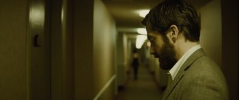 Movie still from “Enemy” (2013), directed by Denis Villeneuve – A person in a hallway; Close Up shot, Over the shoulder angle