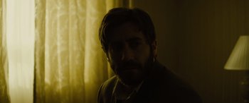 Movie still from “Enemy” (2013), directed by Denis Villeneuve – A person with a beard in the dark; Close Up shot, Over the shoulder angle