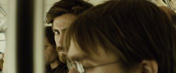 Movie still from “Enemy” (2013), directed by Denis Villeneuve – A person with long hair and a beard; Close Up shot, Over the shoulder angle