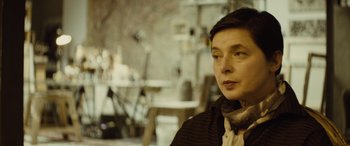 Movie still from “Enemy” (2013), directed by Denis Villeneuve – A woman in a black jacket is looking at the camera; Close Up shot, Low angle