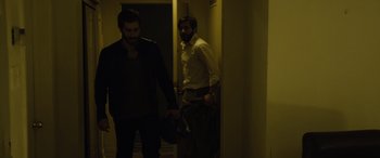 Movie still from “Enemy” (2013), directed by Denis Villeneuve – Two men are standing in a dark hallway; Medium shot, Over the shoulder angle