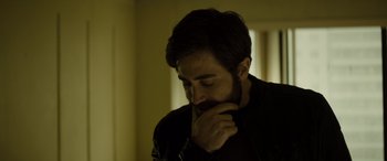 Movie still from “Enemy” (2013), directed by Denis Villeneuve – A person holding his hand to his face; Close Up shot, High angle