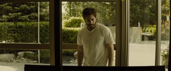 Movie still from “Enemy” (2013), directed by Denis Villeneuve – A man standing in front of an open window; Medium shot, Low angle