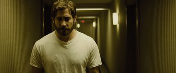 Movie still from “Enemy” (2013), directed by Denis Villeneuve – A man with a beard is standing in a hallway; Close Up shot, Low angle
