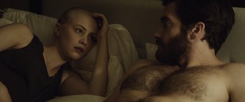 Movie still from “Enemy” (2013), directed by Denis Villeneuve – A man and a woman in bed with one of them looking at the camera; Close Up shot, Over the shoulder angle