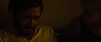 Movie still from “Enemy” (2013), directed by Denis Villeneuve – A man sitting on a couch in a dark room; Close Up shot, High angle