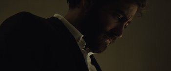 Movie still from “Enemy” (2013), directed by Denis Villeneuve – A person wearing a suit and tie; Close Up shot, Low angle