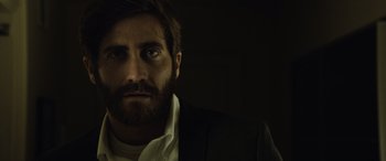 Movie still from “Enemy” (2013), directed by Denis Villeneuve – A person wearing a suit and tie; Close Up shot, Low angle