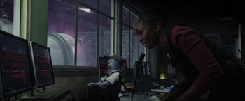 Movie still from “Chip 'n Dale: Rescue Rangers” (2022), directed by Akiva Schaffer – A woman is looking at a robot in a room with windows; Medium shot, Over the shoulder angle