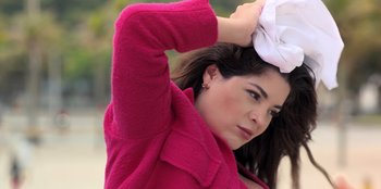 Movie still from “Christmas Full of Grace” (2022), directed by Pedro Antônio Paes – A woman in a pink coat holding a white hat; Close Up shot, Low angle