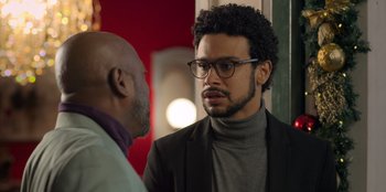 A man with glasses talking to another man in a suit