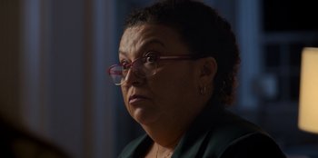 Movie still from “Christmas Full of Grace” (2022), directed by Pedro Antônio Paes – An older woman wearing glasses and a green jacket; Close Up shot, Over the shoulder angle