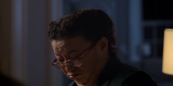 Movie still from “Christmas Full of Grace” (2022), directed by Pedro Antônio Paes – A woman wearing glasses looking down at her face; Close Up shot, Low angle