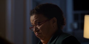 Movie still from “Christmas Full of Grace” (2022), directed by Pedro Antônio Paes – An older woman wearing glasses and a green jacket; Close Up shot, Low angle