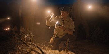 Movie still from “Chupa” (2023), directed by Jonás Cuarón – A man in a hat is holding a flashlight in the dark; Medium shot, Low angle