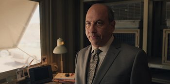 Movie still from “Chupa” (2023), directed by Jonás Cuarón – A man wearing a suit and tie in a room; Close Up shot, Low angle
