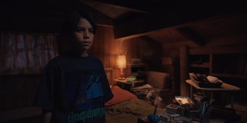 Movie still from “Chupa” (2023), directed by Jonás Cuarón – A young boy standing in a dark room; Medium shot, Over the shoulder angle