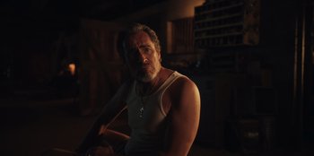 Movie still from “Chupa” (2023), directed by Jonás Cuarón – A person sitting in a room; Close Up shot, Low angle