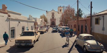 Movie still from “Chupa” (2023), directed by Jonás Cuarón – A group of cars parked on the side of the street; Extreme Wide shot, High angle