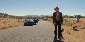 Movie still from “Chupa” (2023), directed by Jonás Cuarón – A man in a cowboy hat standing on the side of the road; Wide shot, Low angle